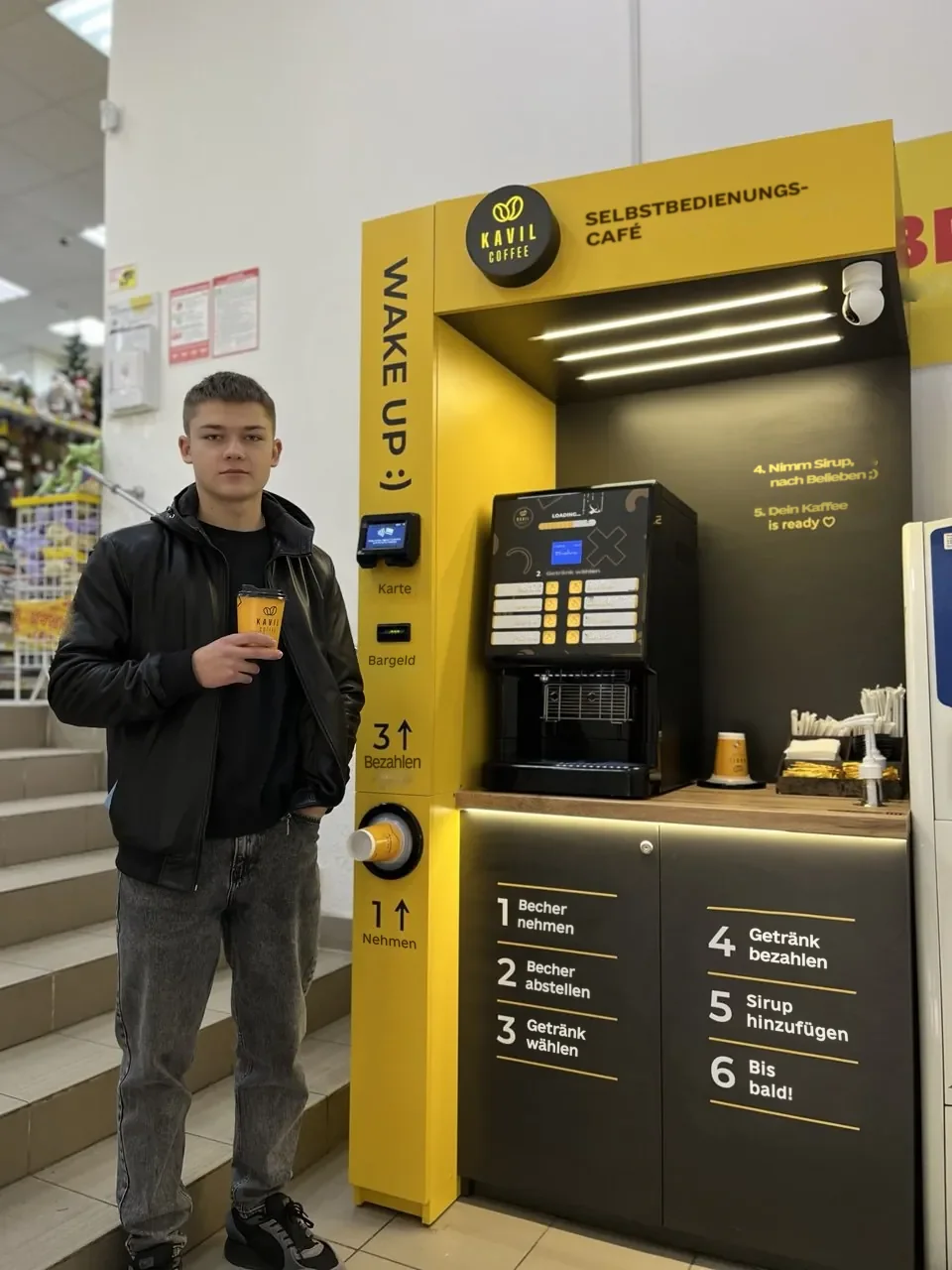 Viktor, Kavil-Partner, mit Kaffee vor seinem Selbstbedienungs-Café